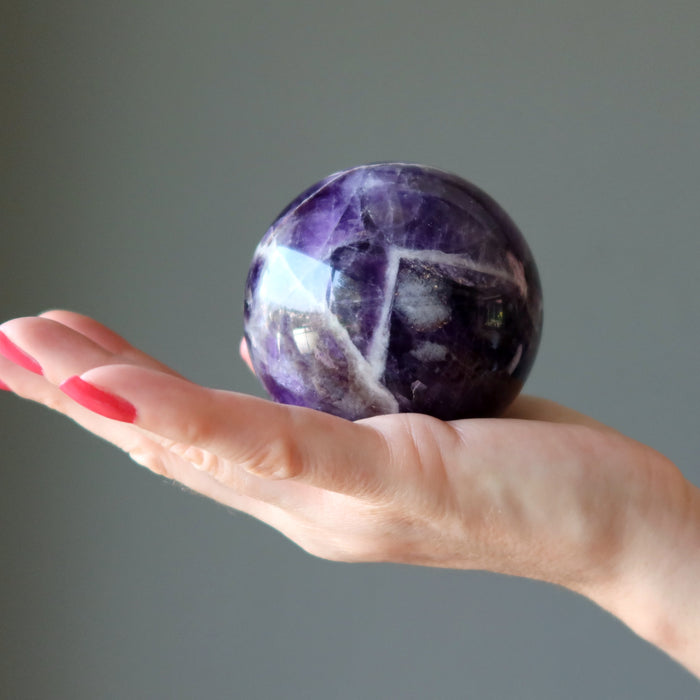 hand holding up a chevron amethyst sphere