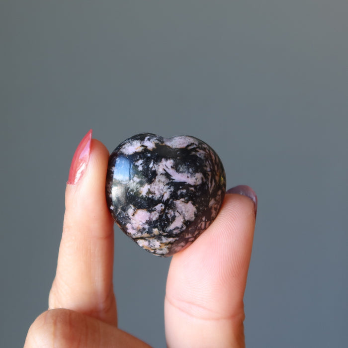 hand holding rhodonite heart
