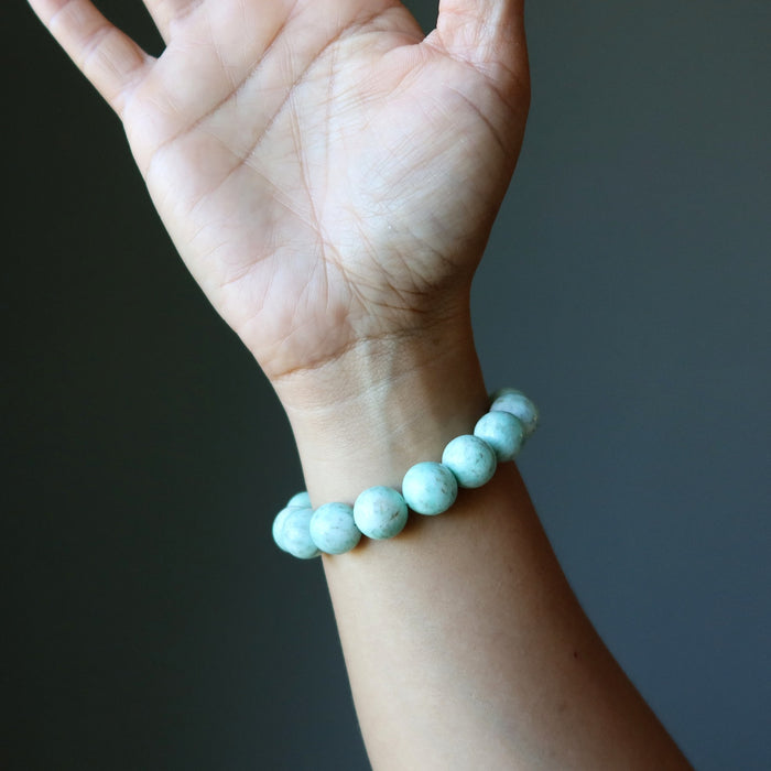 Hand wearing a Green Chrysoprase beaded bracelet against a dark background