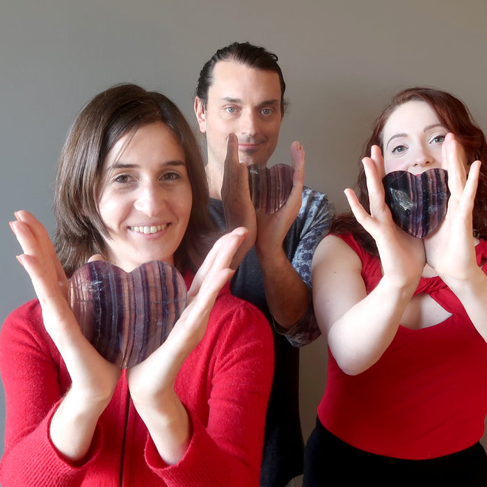 male and two female model each holding Purple Fluorite Heart