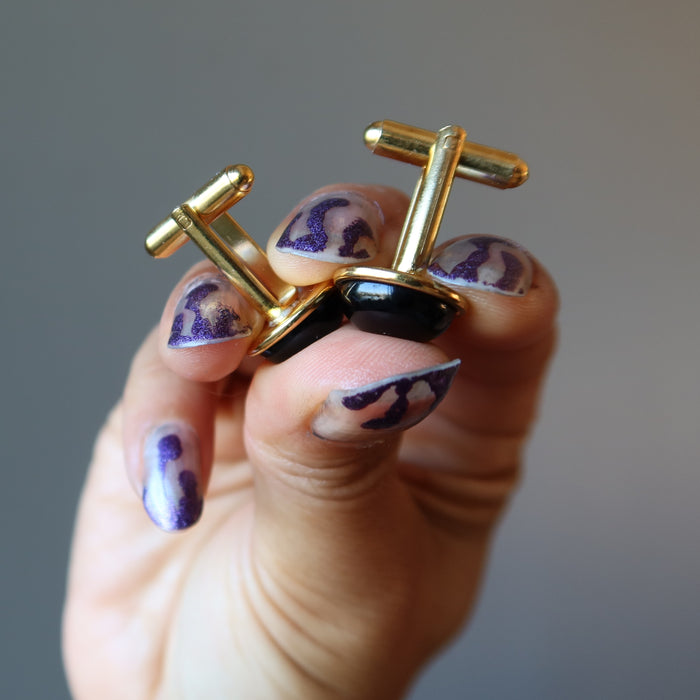 hands holding up black onyx cufflinks