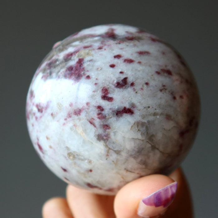 hand holding pink rubellite tourmaline sphere