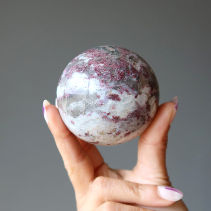 hand holding rubellite tourmaline sphere