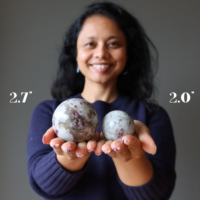 sheila of satin crystals holding a 2.7" and a 2.0" rubellite tourmaline sphere